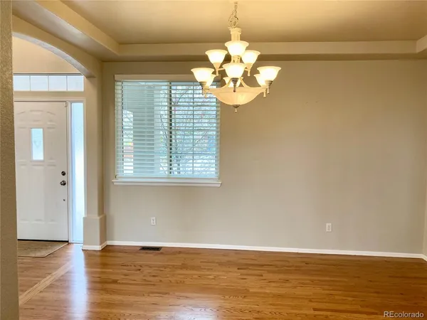 a view of a livingroom with a chandelier wooden floor and windows