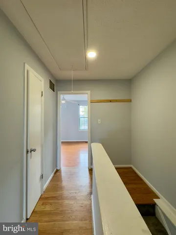a view of a hallway with wooden floor and staircase