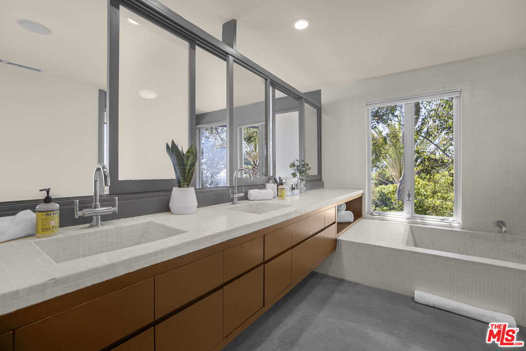 9892 Beverly Grove Drive Beverly Hills, CA 90210 - Photo 13 of 39 a bathroom with double vanity sinks a large mirror and a window