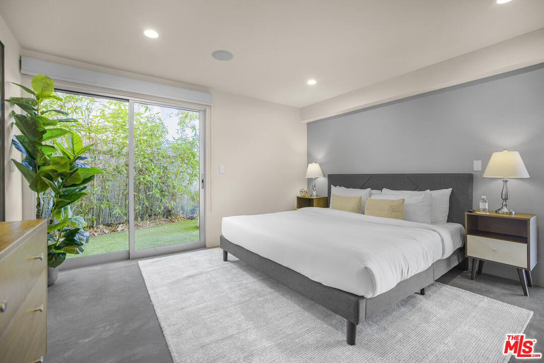9892 Beverly Grove Drive Beverly Hills, CA 90210 - Photo 20 of 39 a spacious bedroom with a bed and a lamp