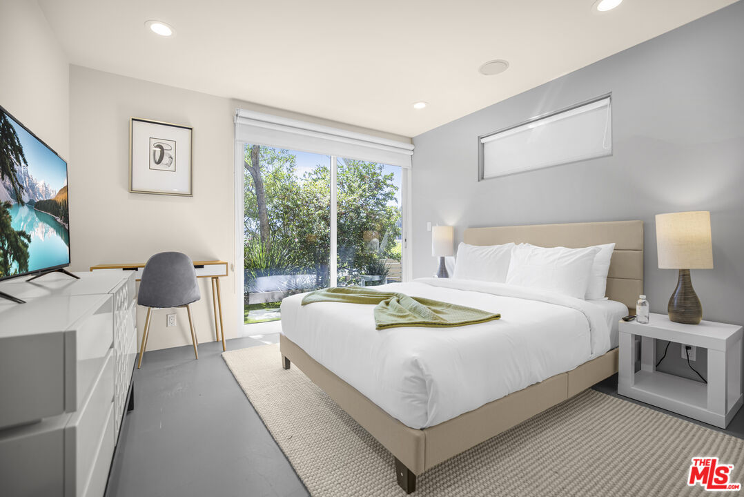 9892 Beverly Grove Drive Beverly Hills, CA 90210 - Photo 26 of 39 a bedroom with bed a table and a large window