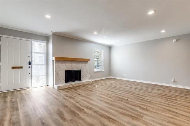a view of an empty room with wooden floor fireplace and a window