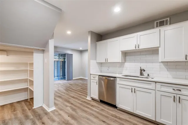 a kitchen with white cabinets and sink