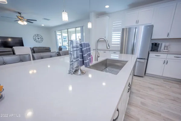 a kitchen with stainless steel appliances a sink dishwasher a refrigerator and a dining table with wooden floor