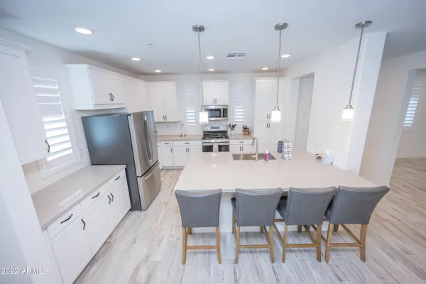 a kitchen with stainless steel appliances a dining table chairs and wooden floor