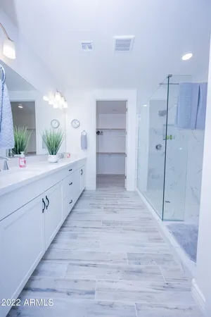 a spacious bathroom with a double vanity sink a large mirror and shower