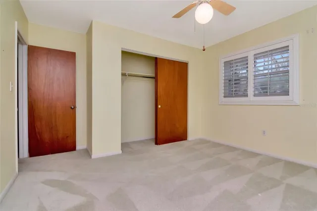 an empty room with closet and a chandelier fan