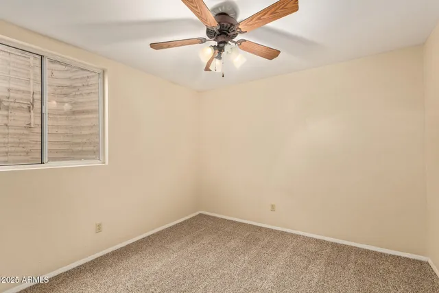 an empty room with a window and a ceiling fan