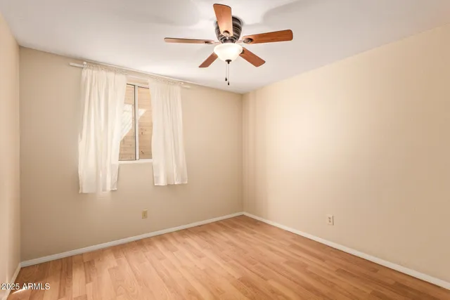 an empty room with a window and a ceiling fan