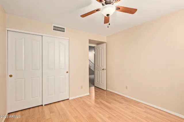 an empty room with a ceiling fan and wooden floor