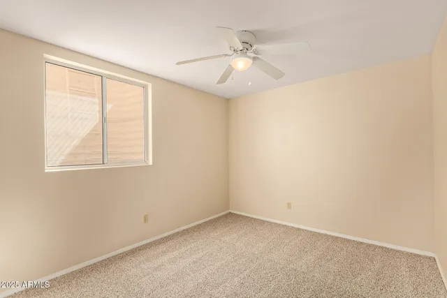 an empty room with windows and fan