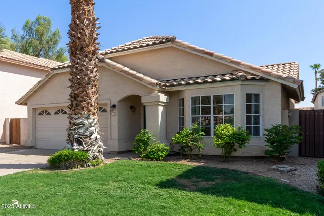 a front view of a house with a yard and potted plants
