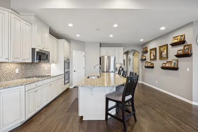 a large kitchen with kitchen island granite countertop lots of white cabinets appliances and furniture