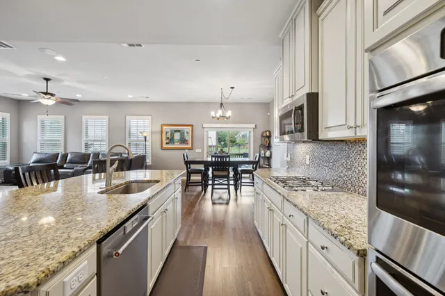 a large kitchen with stainless steel appliances granite countertop a lot of counter space and wooden floor