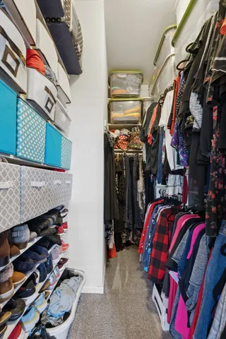 a view of walk in closet with clothes and shoes
