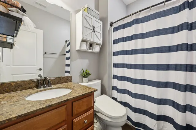 a bathroom with a granite countertop toilet a sink and a mirror