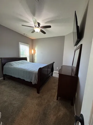 a bedroom with a bed tv and a window