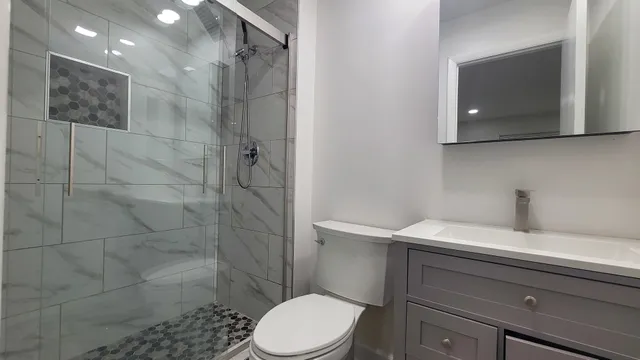 a view of an empty room with wooden floor and a bathroom