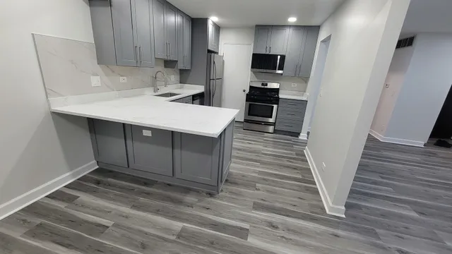 a kitchen with stainless steel appliances a sink cabinets and wooden floor