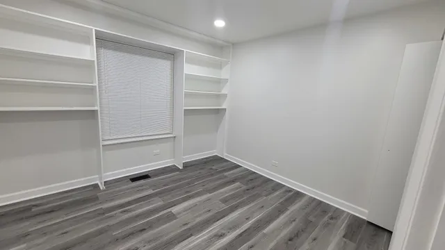 a view of an empty room with wooden floor and a mirror