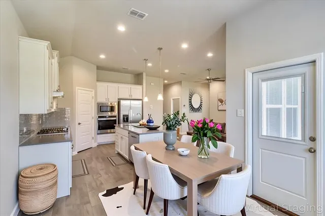 a view of a dining room with furniture a potted plant and wooden floor