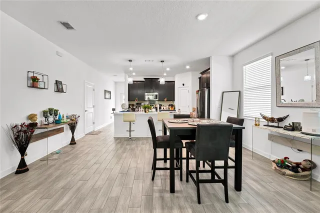 a kitchen with stainless steel appliances kitchen island granite countertop a table chairs and a refrigerator