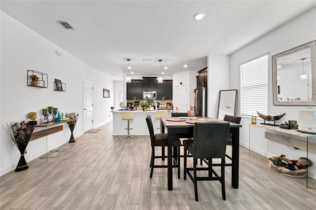 5656 Quiet Palm Loop St. Cloud, FL 34771 - Photo 11 of 36 a kitchen with stainless steel appliances kitchen island granite countertop a table chairs and a refrigerator