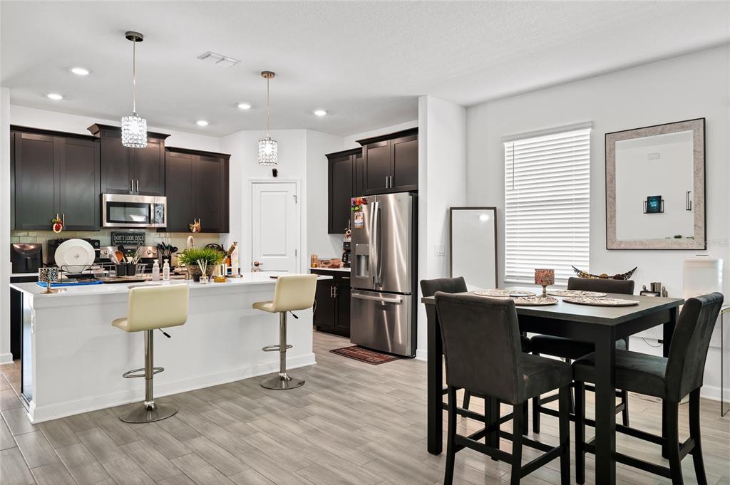 5656 Quiet Palm Loop St. Cloud, FL 34771 - Photo 12 of 36 a kitchen with stainless steel appliances kitchen island granite countertop a table chairs refrigerator and sink