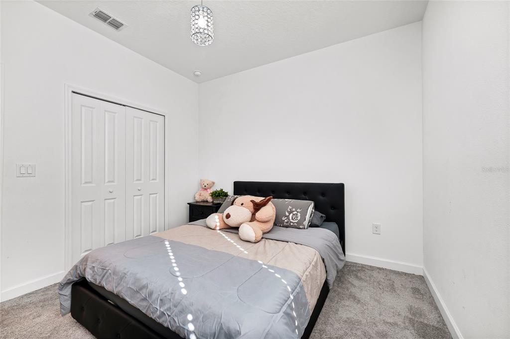 5656 Quiet Palm Loop St. Cloud, FL 34771 - Photo 17 of 36 a bedroom with a bed and a night stand