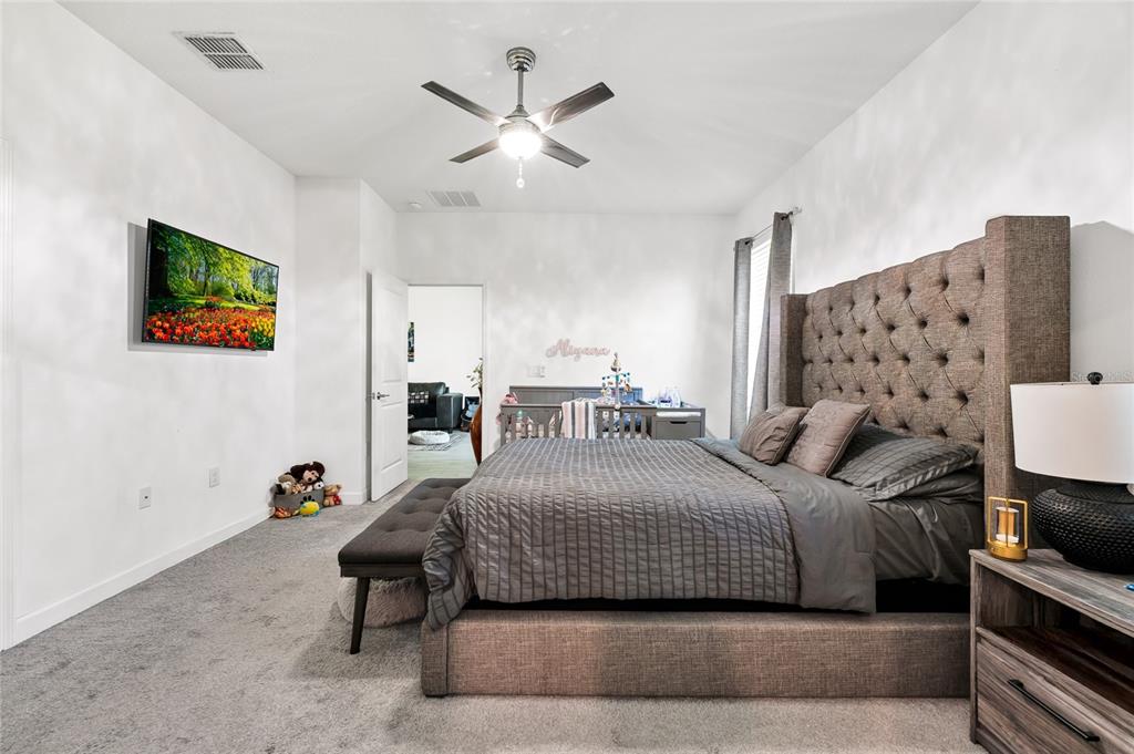 5656 Quiet Palm Loop St. Cloud, FL 34771 - Photo 24 of 36 a bedroom with a bed and a chandelier