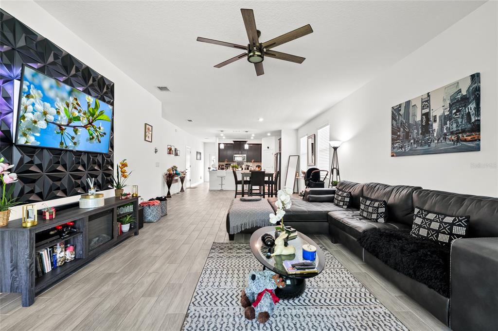 5656 Quiet Palm Loop St. Cloud, FL 34771 - Photo 6 of 36 a living room with furniture a flat screen tv and a fireplace