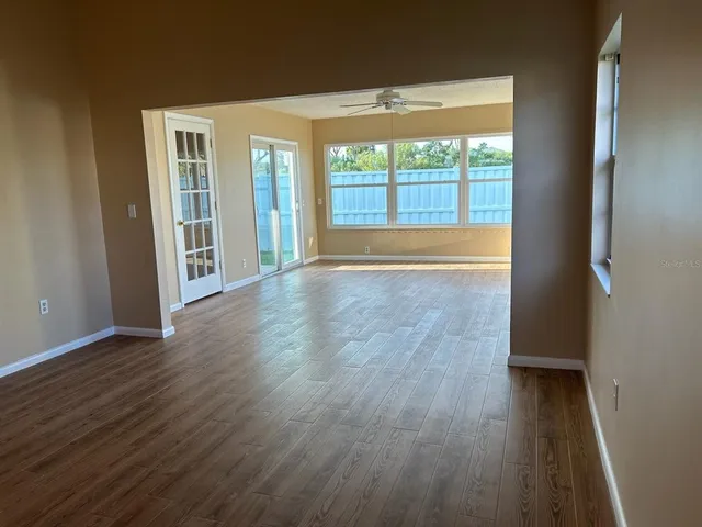 an empty room with wooden floor and windows