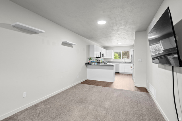64 West 600 South, Unit C205 Springville, UT 84663 - Photo 27 of 28 Kitchen with white cabinets, light colored carpet, open floor plan, a textured ceiling, and dark countertops
