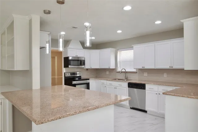 a kitchen with granite countertop white cabinets white stainless steel appliances and a sink