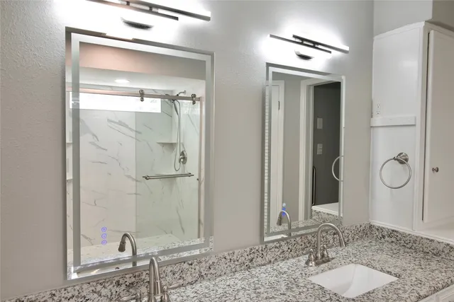 a bathroom with a granite countertop sink a large mirror and a shower