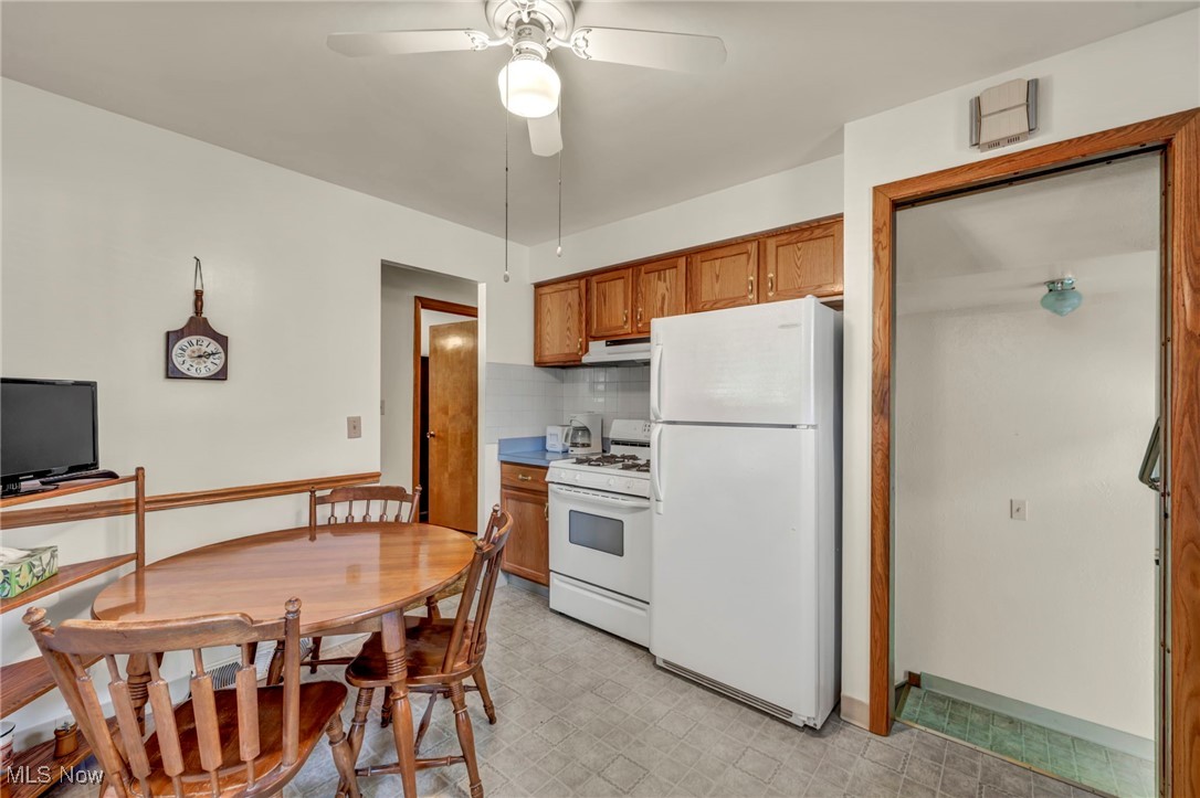 13732 Carpenter Road Garfield Heights, OH 44125 - Photo 15 of 46 Kitchen with brown cabinets, white appliances, decorative backsplash, a ceiling fan, and light countertops