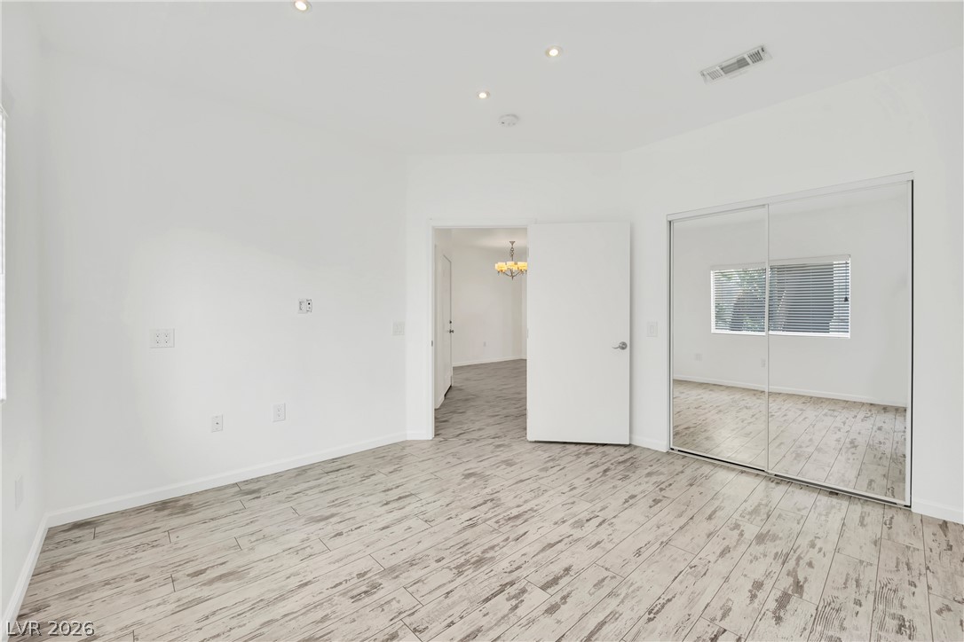 8725 West Flamingo Road, Unit 110 Las Vegas, NV 89147 - Photo 12 of 30 Recessed lighting and distressed-look wood flooring illuminate a comfortable bedroom, complete with mirrored closet doors.