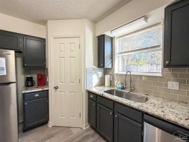 a kitchen with granite countertop a sink stainless steel appliances and cabinets