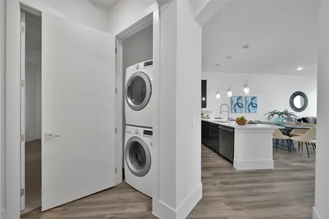 a room with kitchen island with stainless steel appliances granite countertop a sink and wooden floor