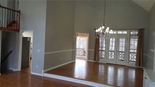 a view of a room with wooden floor chandelier and windows