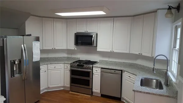 a kitchen with granite countertop a sink stove and refrigerator