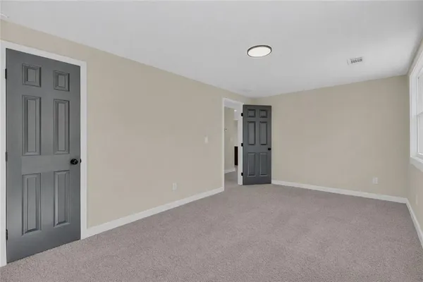 a view of an empty room with closet and a window