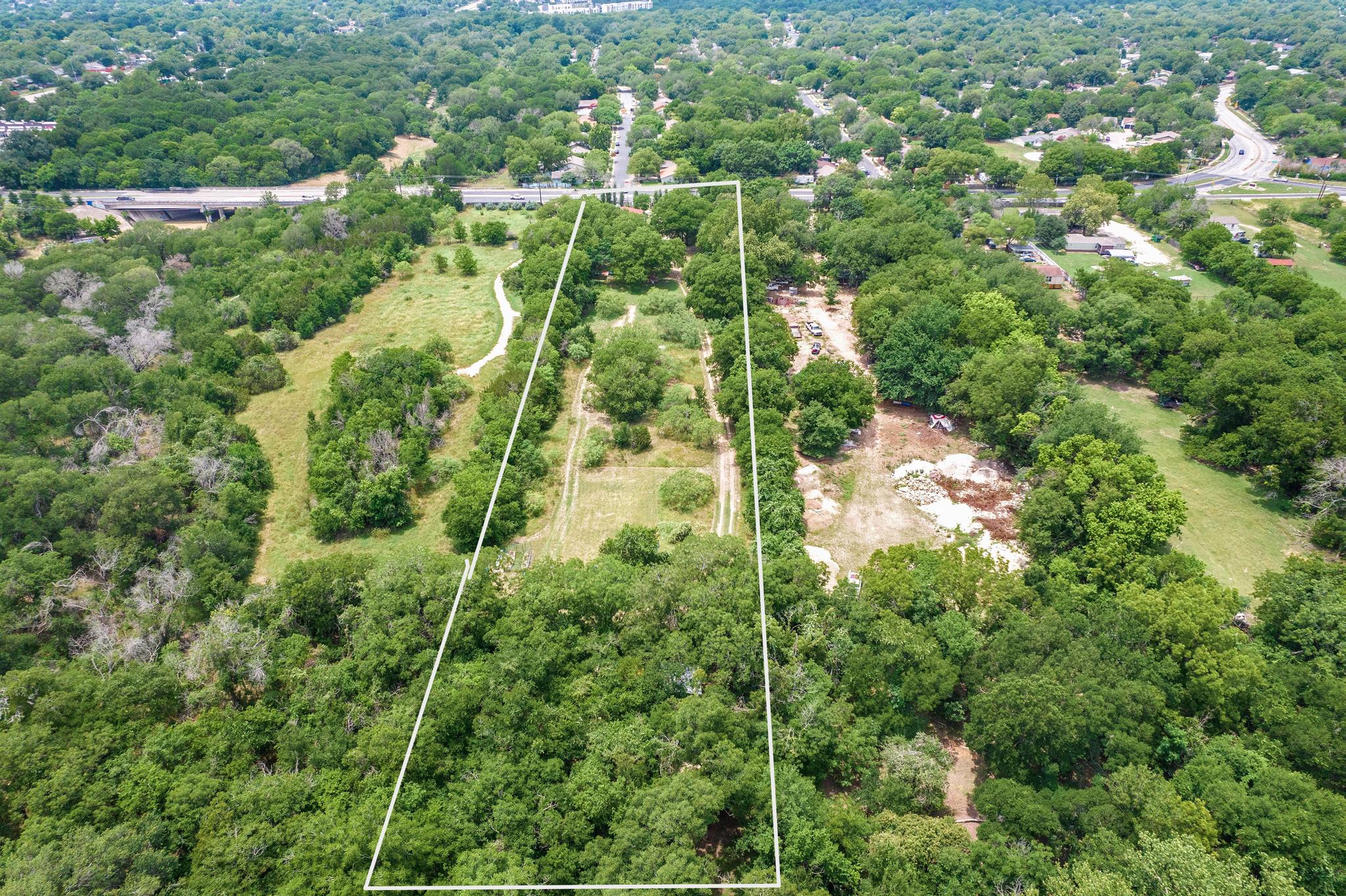 an aerial view of residential houses with outdoor space and trees all around