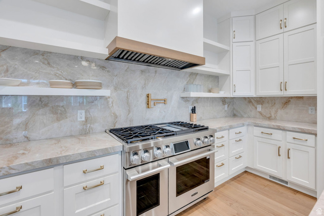 250 South Main Street, Unit 10 Alpine, UT 84004 - Photo 6 of 29 Gourmet kitchen featuring a stainless steel range with a built-in double oven, full-height veined backsplash, matching countertops, white shaker cabinetry with brass hardware, and wood-finish flooring