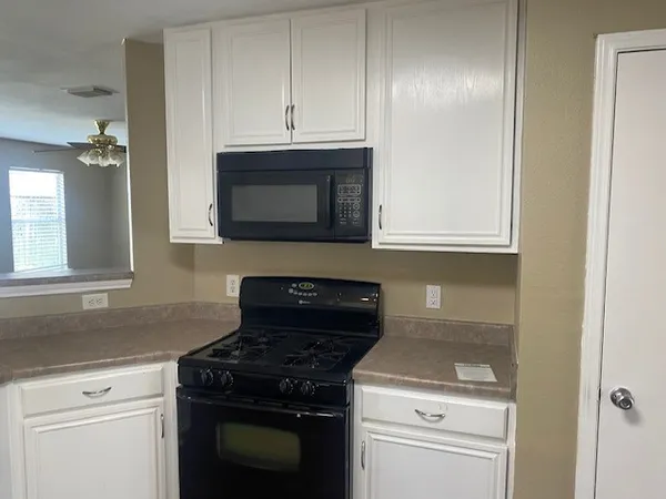 a kitchen with granite countertop white cabinets and stainless steel appliances