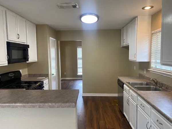 a kitchen with granite countertop a sink a stove and cabinets