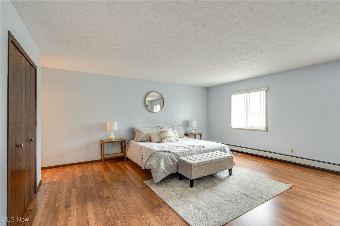 308 Guy's Run Road Akron, OH 44319 - Photo 23 of 44 Bedroom with a baseboard radiator, wood finished floors, a textured ceiling, a closet, and baseboards