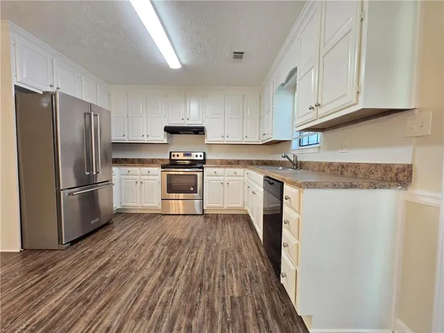 a kitchen with wooden floors white cabinets and stainless steel appliances