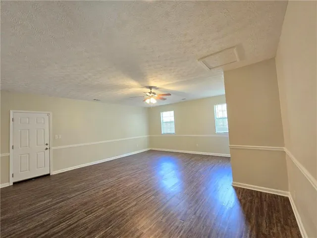 an empty room with wooden floor ceiling fan and windows