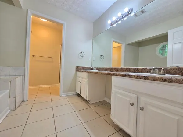 a bathroom with a granite countertop sink a mirror and a bathtub